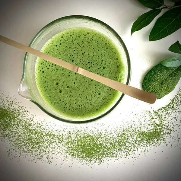 Glazen matcha kom van borosilicaat glas gevuld met match en bamboelepel.