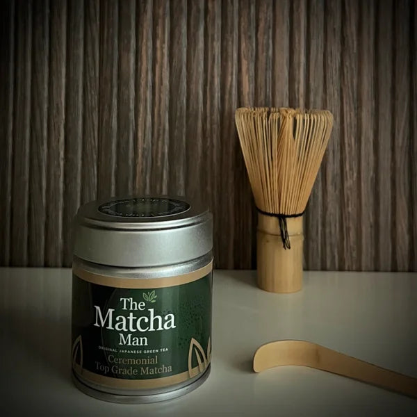 Japanse matcha set van The Matcha Man, bestaande uit zilverkleurig blikje 'Ceremonial Top Grade Matcha' (30 gram), een bamboelepel en een whisk op de achtergrond.